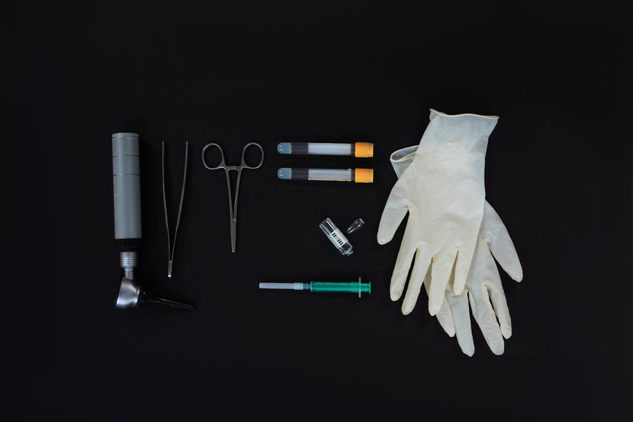 about-01 Flat lay of essential medical tools on a black background, including gloves and syringe.